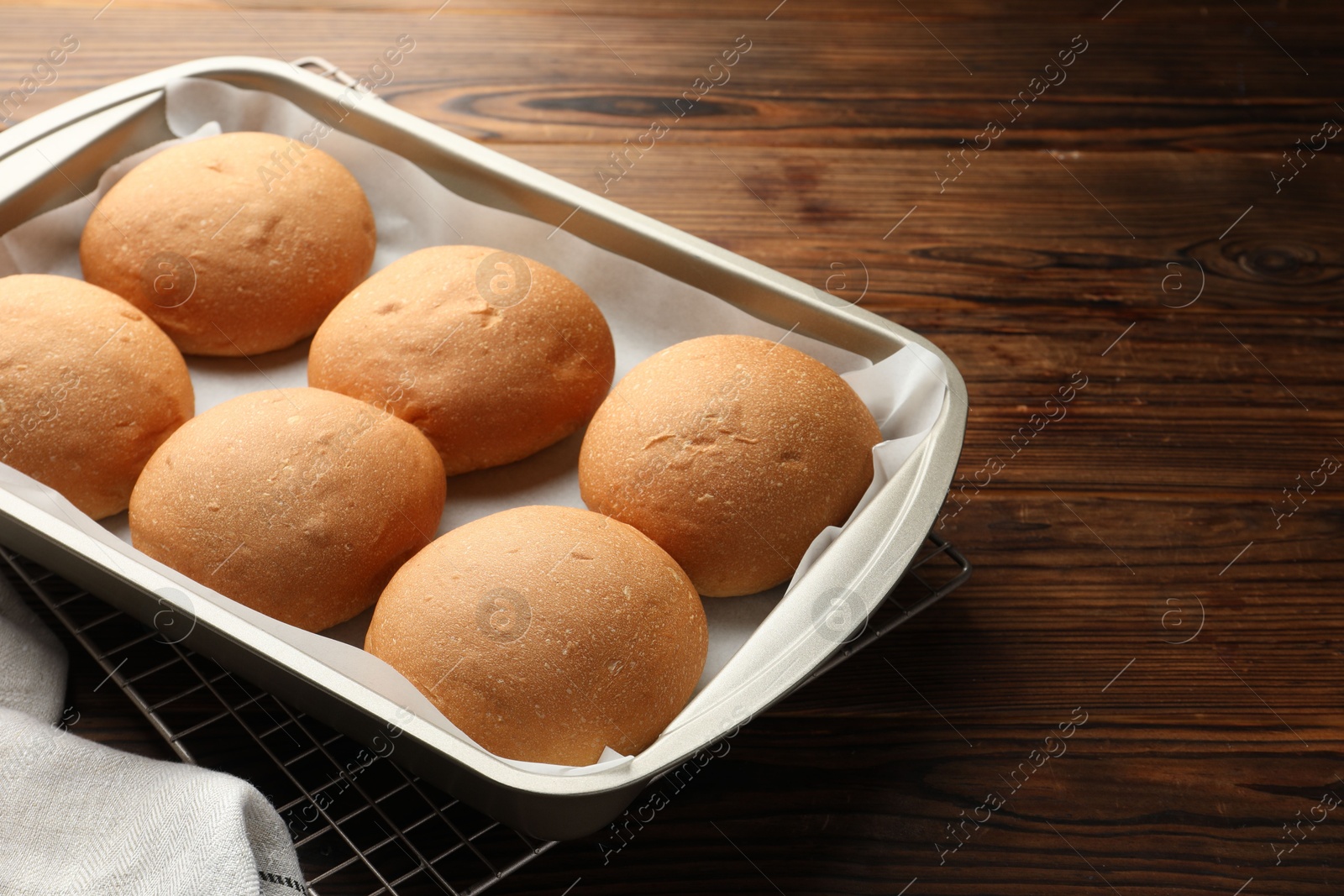 Photo of Fresh tasty buns in baking tray on wooden table, closeup