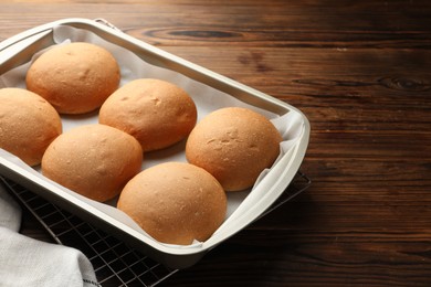 Fresh tasty buns in baking tray on wooden table, closeup