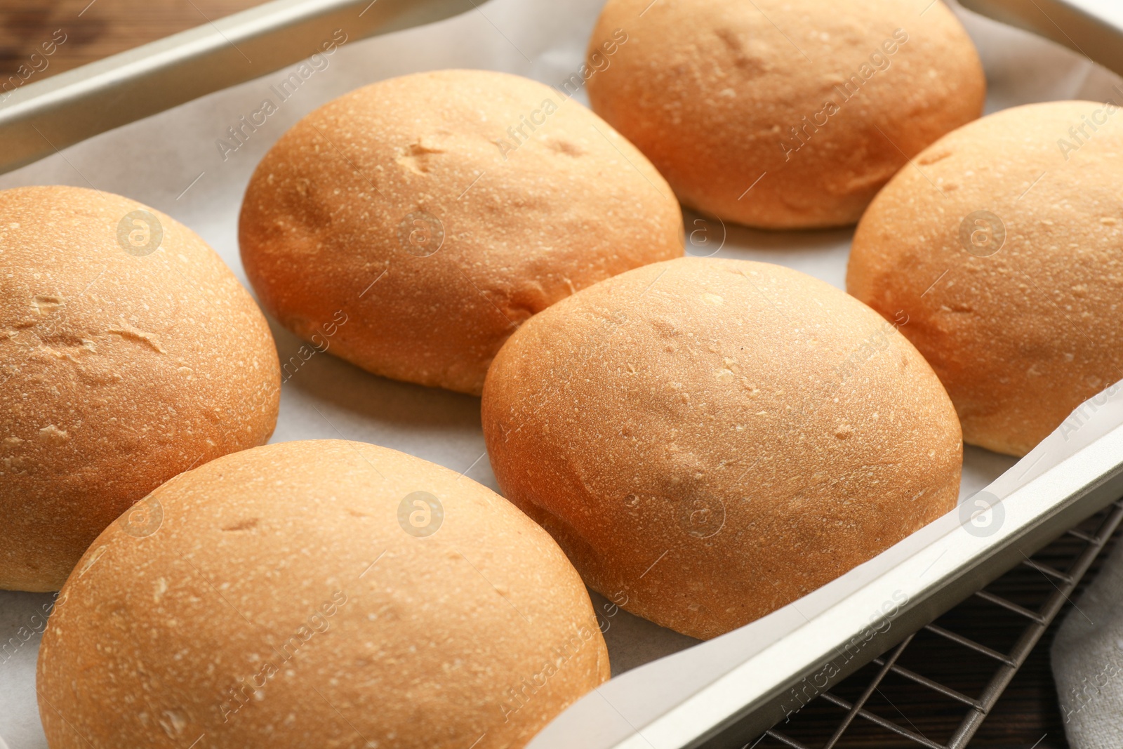 Photo of Fresh tasty buns in baking tray on table, closeup