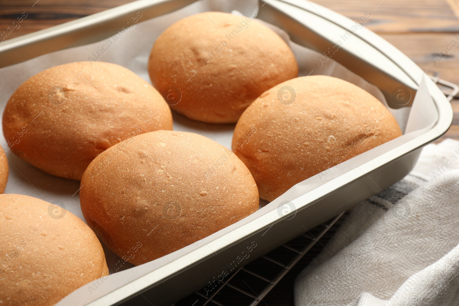 Photo of Fresh tasty buns in baking tray on table, closeup