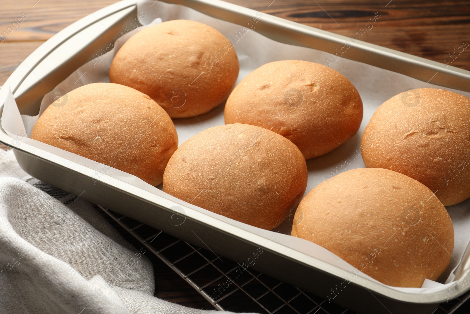 Photo of Fresh tasty buns in baking tray on table, closeup