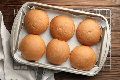 Fresh tasty buns in baking tray on wooden table, top view