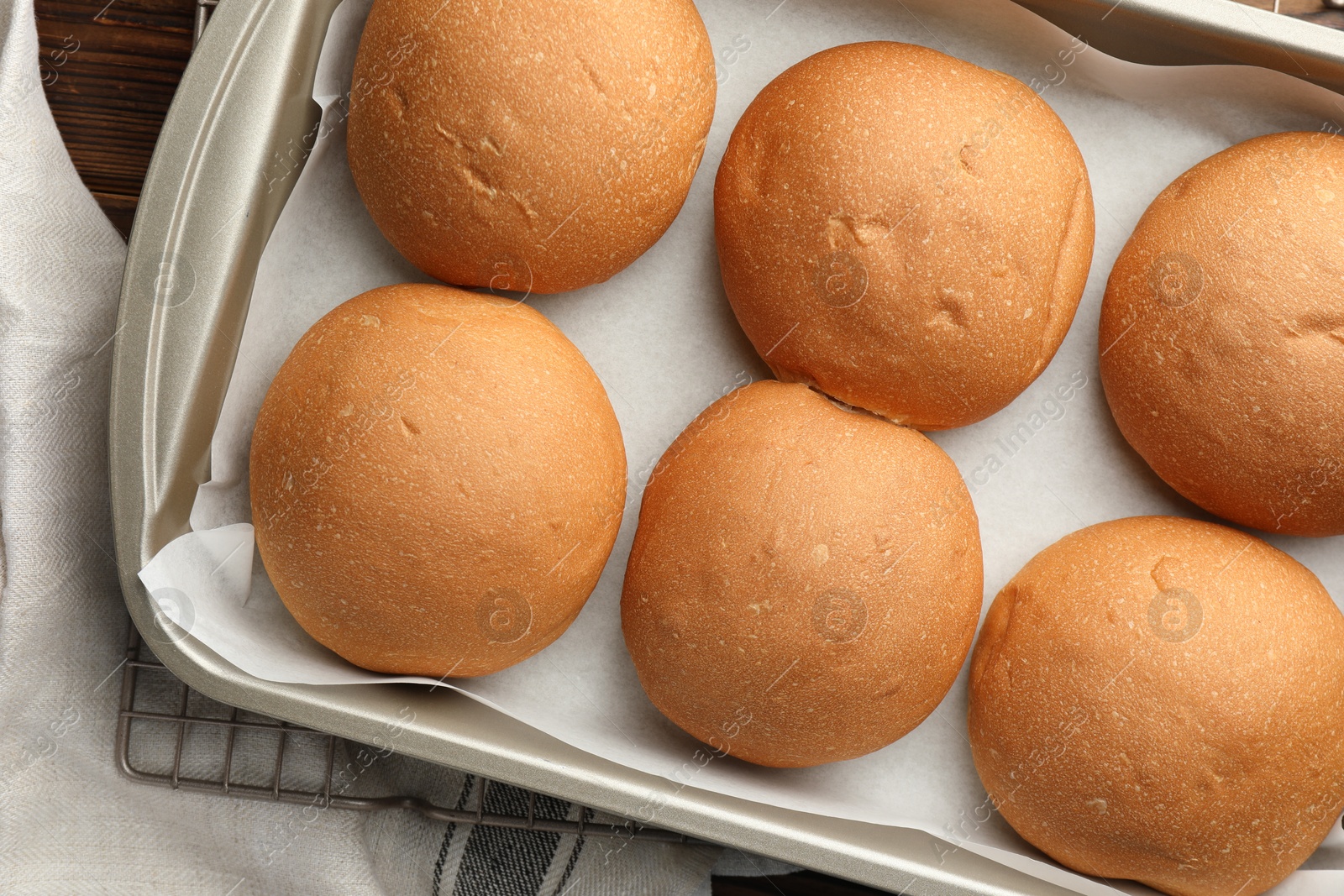 Photo of Fresh tasty buns in baking tray on table, top view