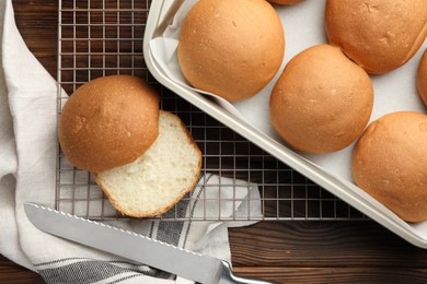 Fresh tasty buns in baking tray on wooden table, top view