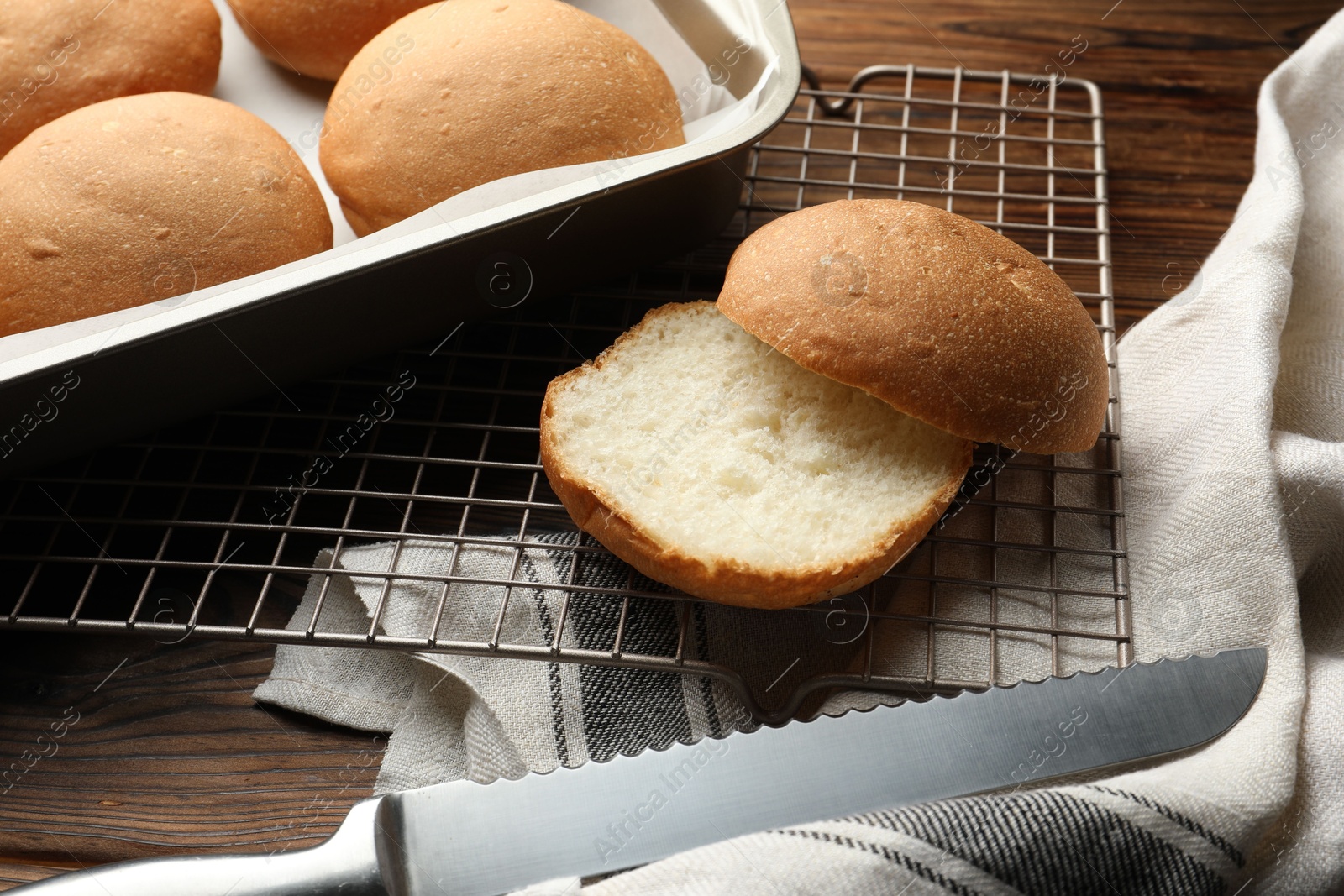 Photo of Fresh tasty buns and knife on wooden table, closeup