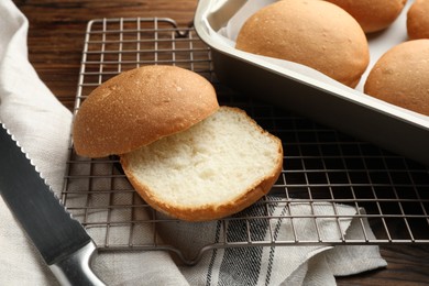 Photo of Fresh tasty buns and knife on wooden table, closeup