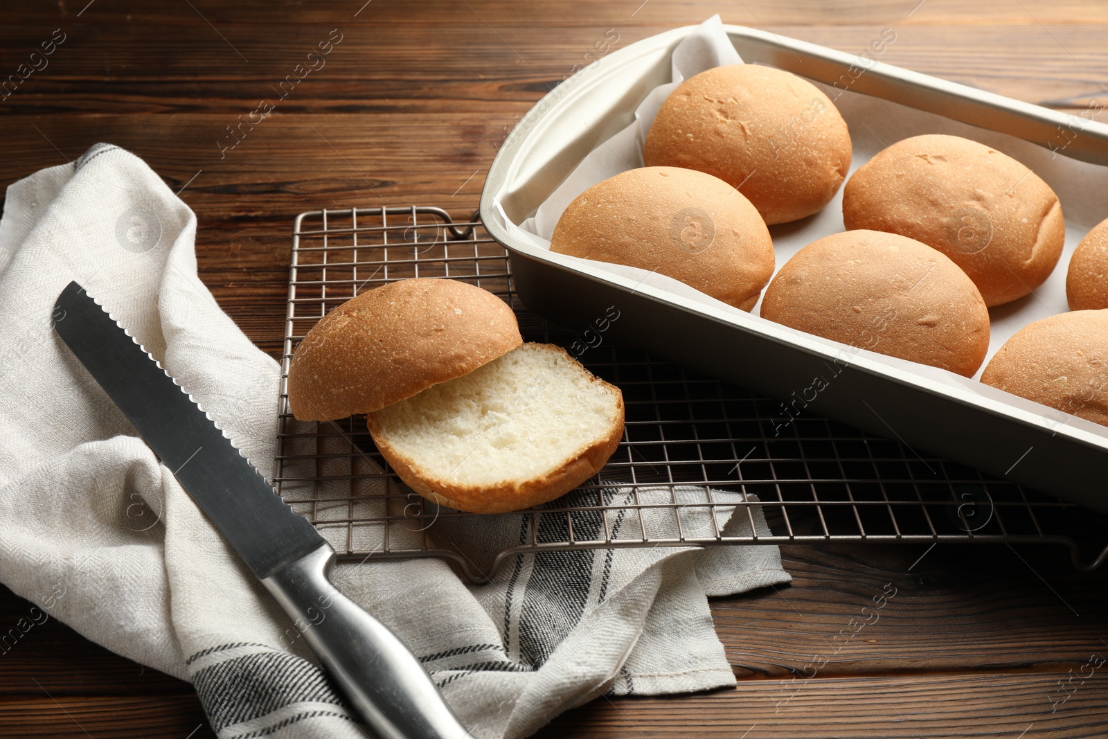 Photo of Fresh tasty buns and knife on wooden table