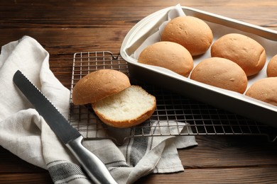 Fresh tasty buns and knife on wooden table