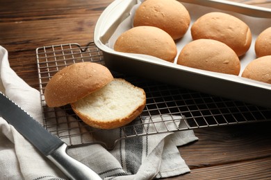 Photo of Fresh tasty buns and knife on wooden table