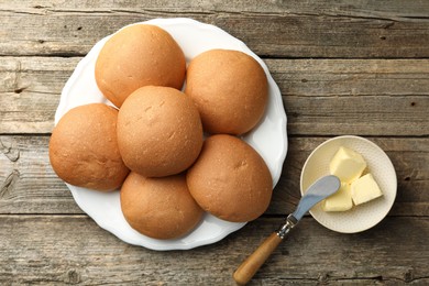 Photo of Fresh tasty buns and butter on wooden table, top view