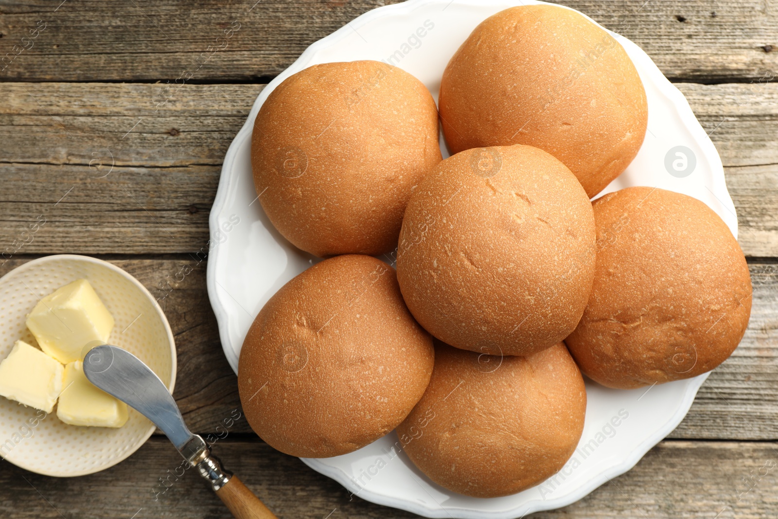 Photo of Fresh tasty buns and butter on wooden table, top view