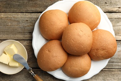 Photo of Fresh tasty buns and butter on wooden table, top view