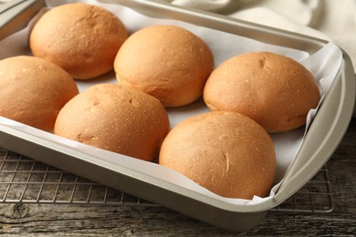 Fresh tasty buns in baking dish on wooden table, closeup