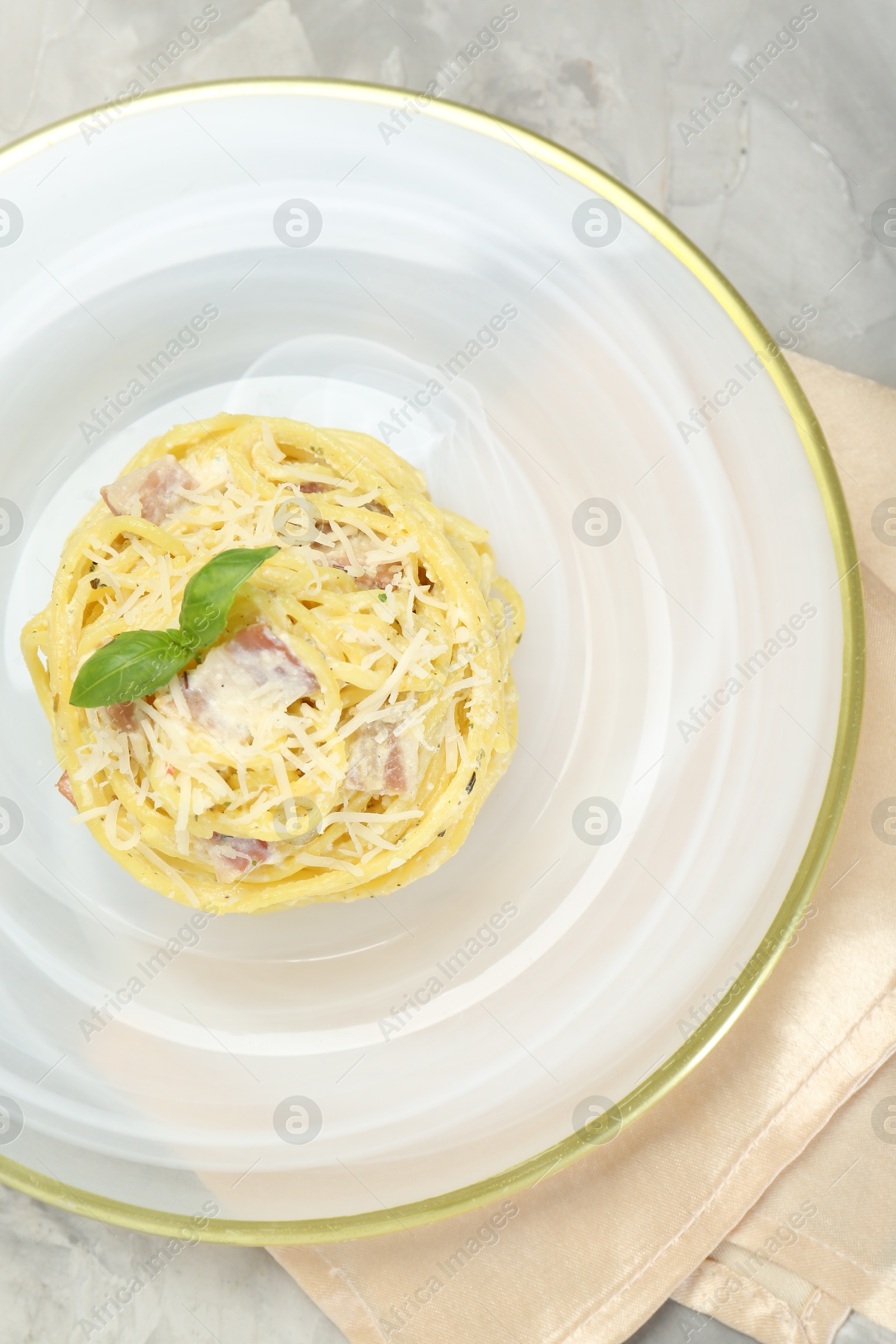 Photo of Plate with delicious pasta Carbonara on grey table, top view