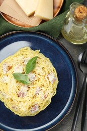 Photo of Plate with delicious pasta Carbonara, oil and cheese on grey textured table, flat lay