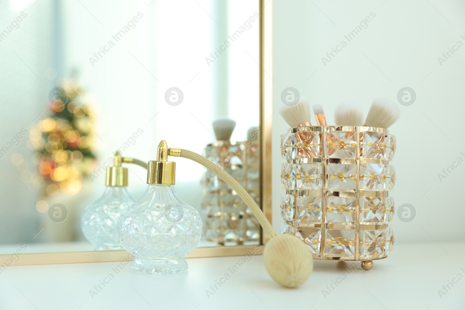 Photo of Makeup brushes and perfume on white table indoors