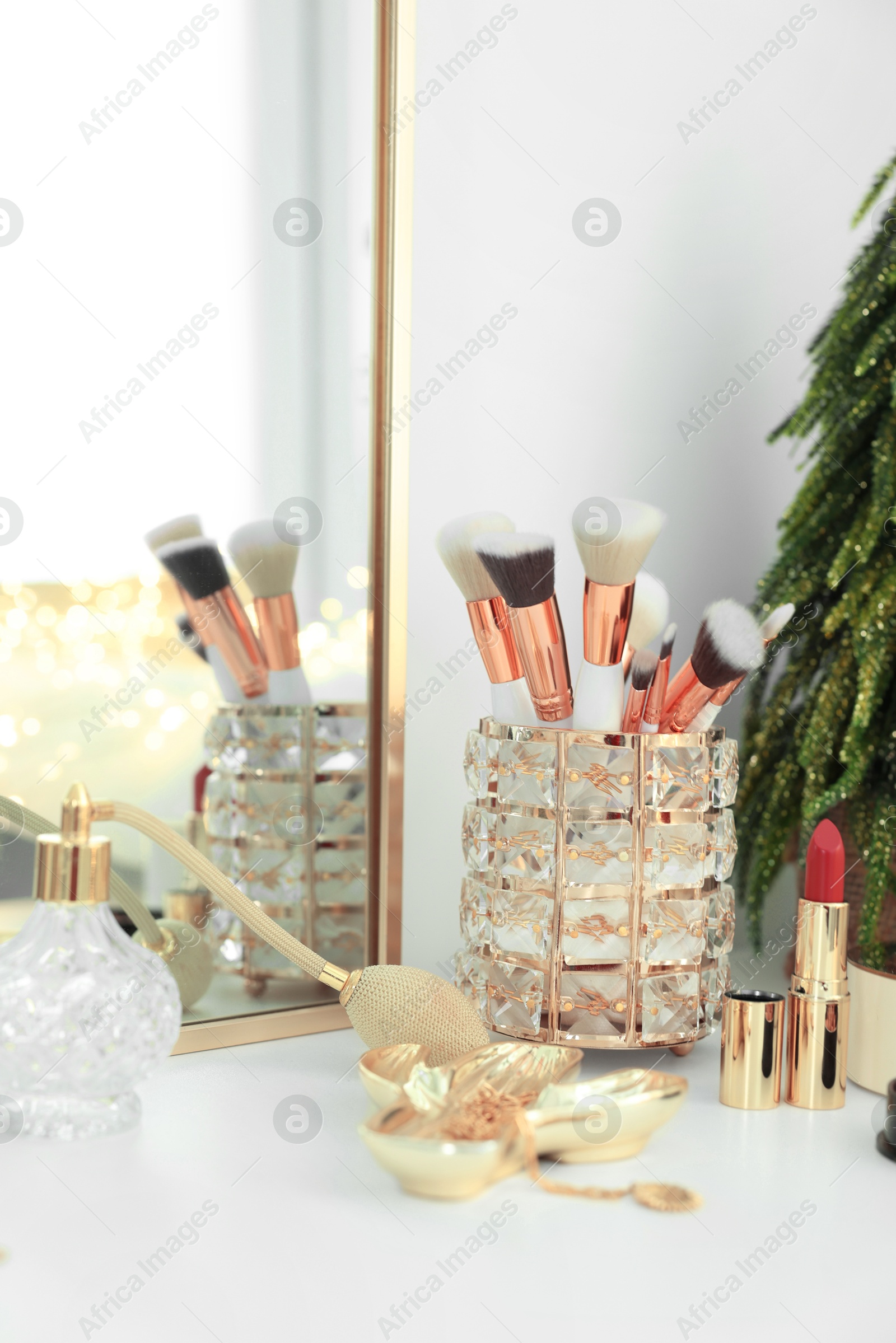 Photo of Makeup brushes and perfume on white table indoors