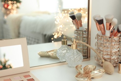 Photo of Makeup brushes and perfume on white table indoors