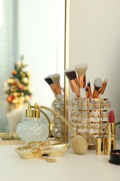 Photo of Makeup brushes and perfume on white table indoors