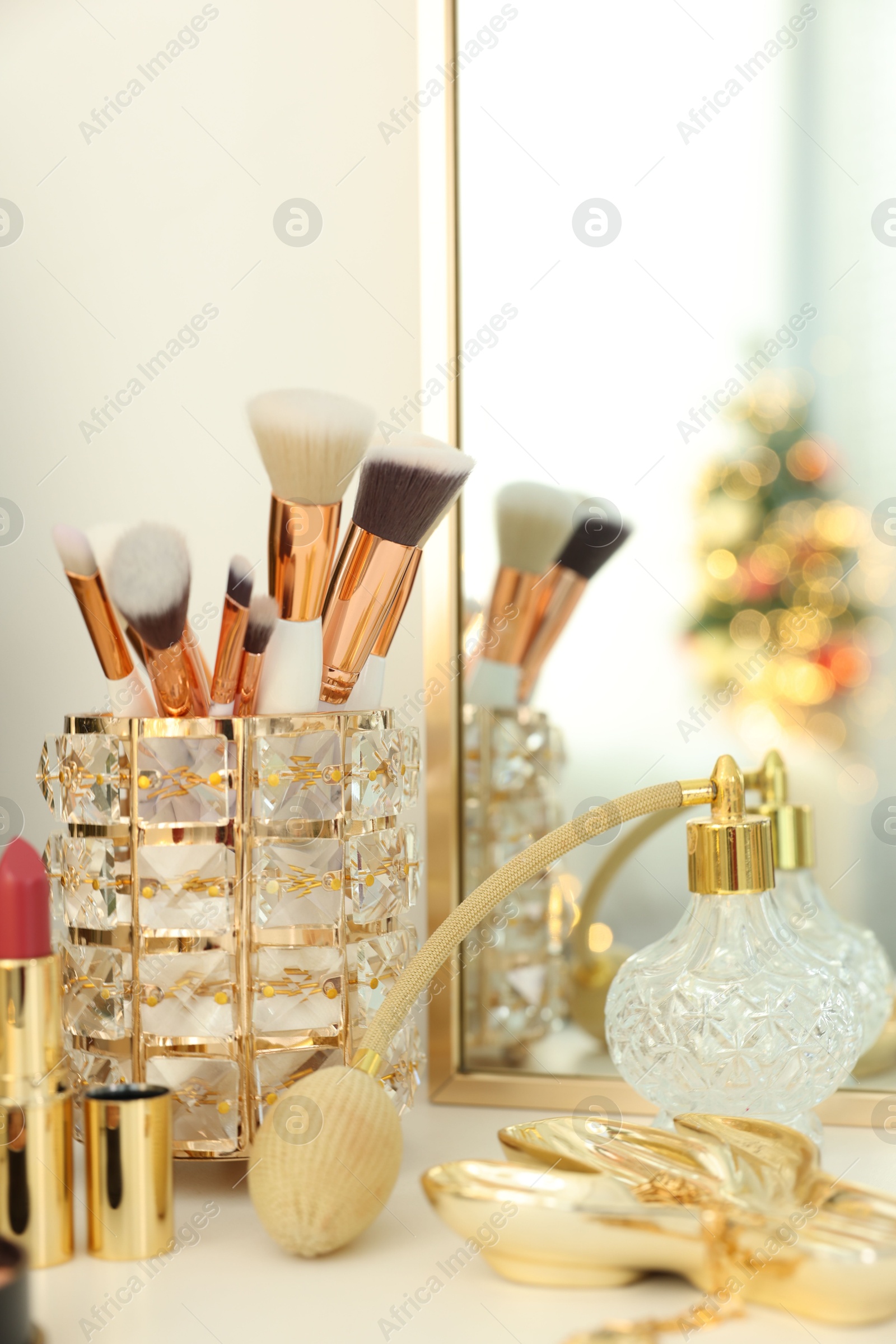 Photo of Makeup brushes and perfume on white table indoors