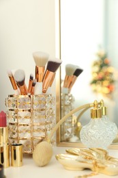 Photo of Makeup brushes and perfume on white table indoors