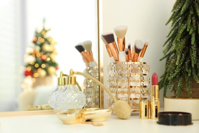 Photo of Makeup brushes and perfume on white table indoors