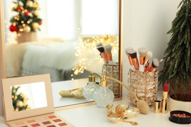 Photo of Makeup brushes and perfume on white table indoors