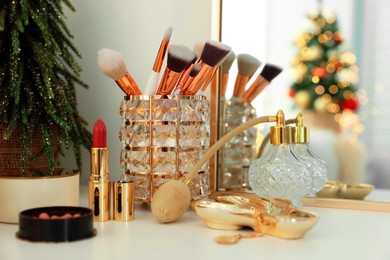 Photo of Makeup brushes and perfume on white table indoors