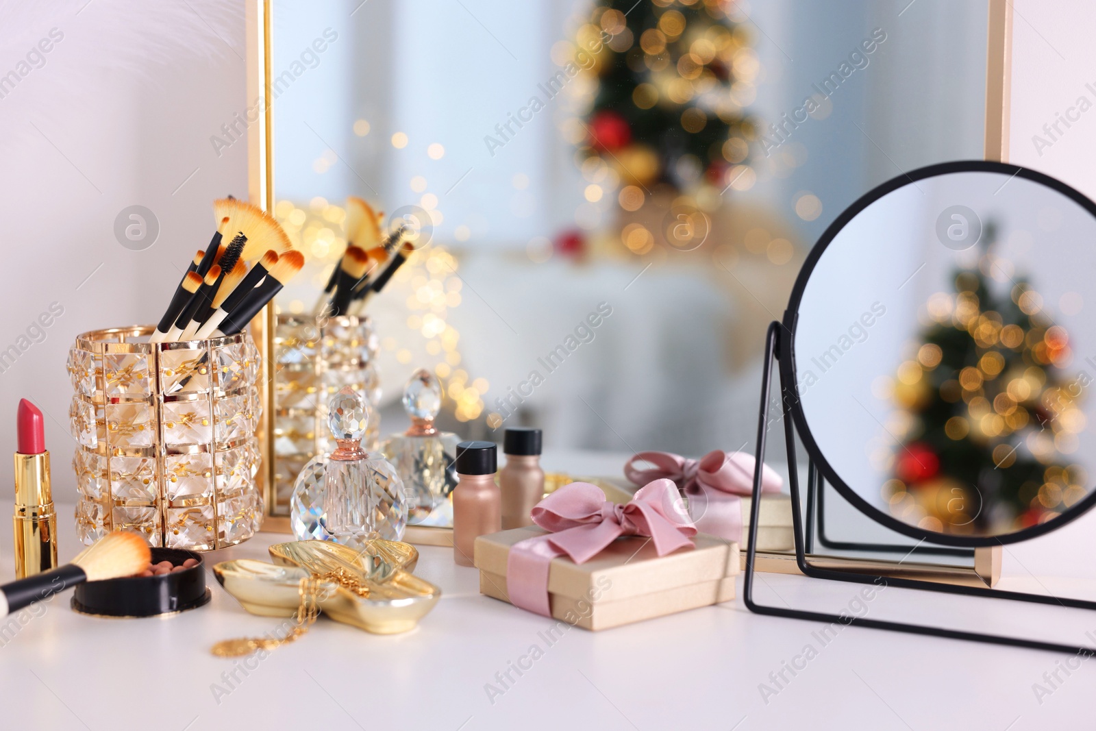 Photo of Makeup brushes, cosmetics, mirror and perfume on white table indoors