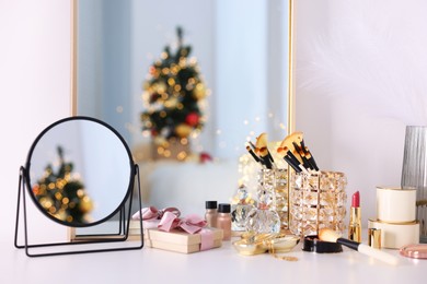 Photo of Makeup brushes, cosmetics, mirror and perfume on white table indoors