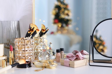 Photo of Makeup brushes, cosmetics, mirror and perfume on white table indoors