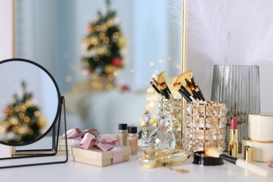 Photo of Makeup brushes, cosmetics, mirror and perfume on white table indoors