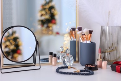 Photo of Makeup brushes, cosmetics, mirror and perfume on white table indoors