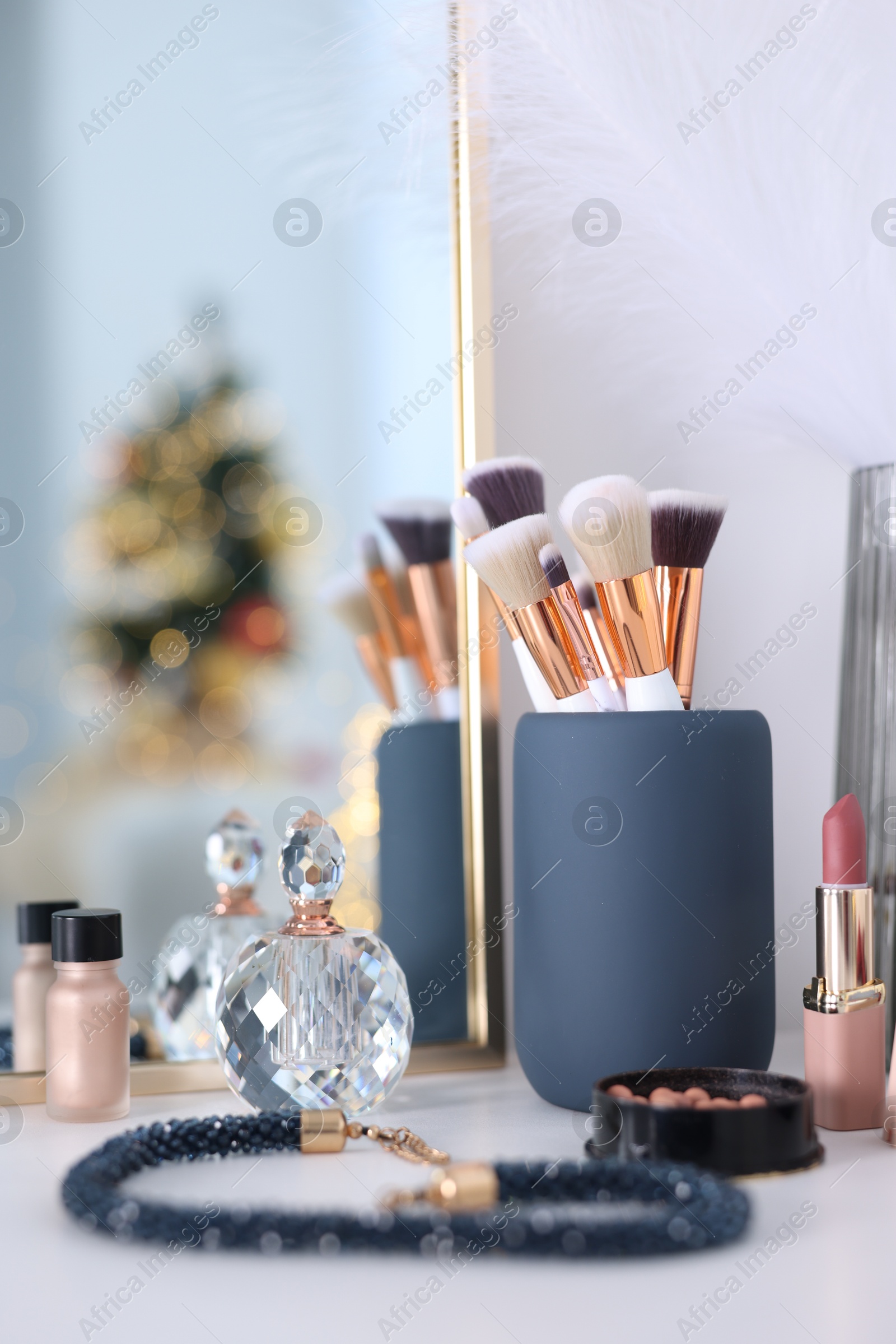 Photo of Makeup brushes, cosmetics and perfume on white table indoors