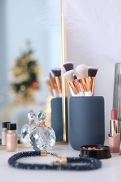 Photo of Makeup brushes, cosmetics and perfume on white table indoors