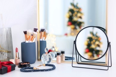 Photo of Makeup brushes, cosmetics, mirror and perfume on white table indoors