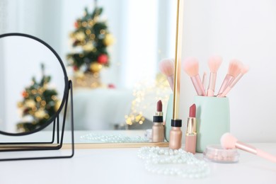 Photo of Makeup brushes, cosmetics and mirror on white table indoors