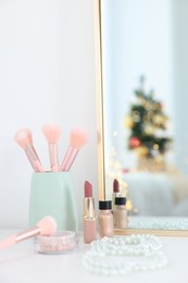 Photo of Makeup brushes, cosmetics and mirror on white table indoors