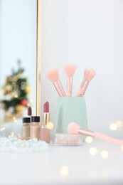 Photo of Makeup brushes, cosmetics and mirror on white table indoors