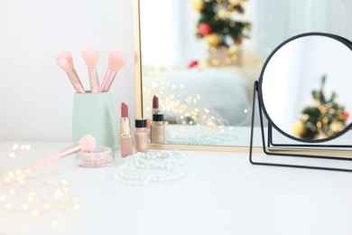 Photo of Makeup brushes, cosmetics and mirror on white table indoors