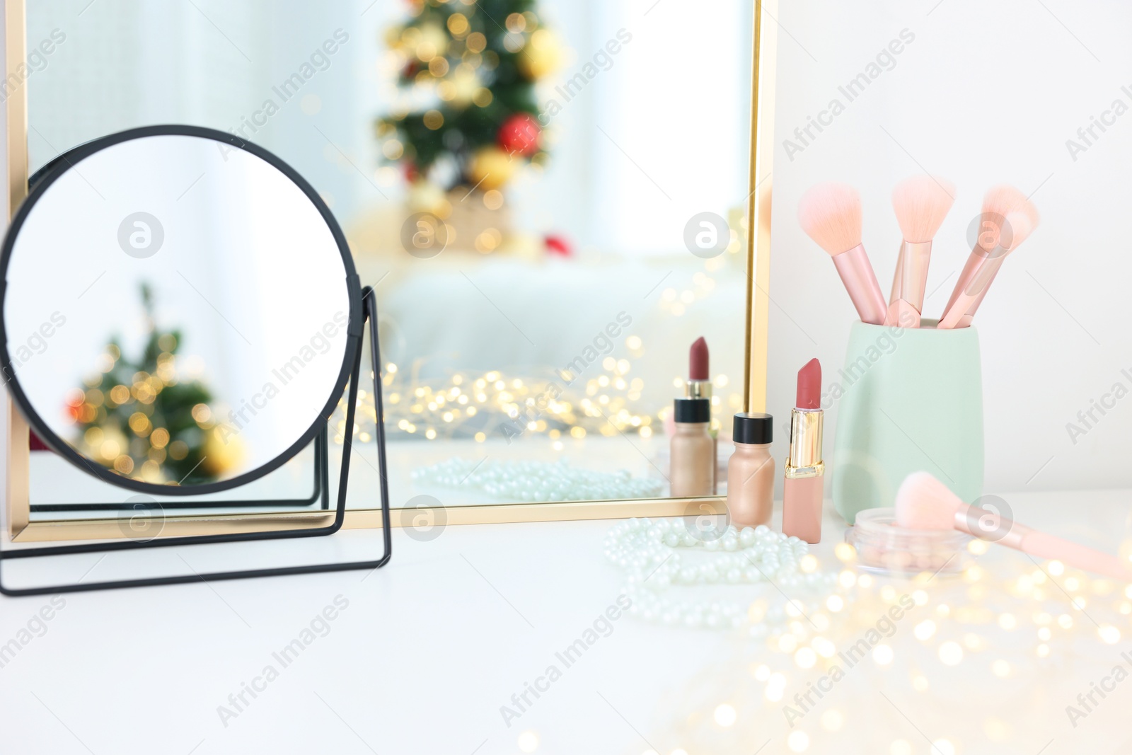 Photo of Makeup brushes, cosmetics and mirror on white table indoors