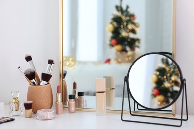 Photo of Makeup brushes, cosmetics, mirror and perfume on white table indoors