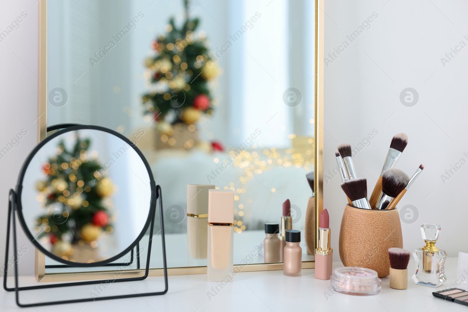 Photo of Makeup brushes, cosmetics, mirror and perfume on white table indoors