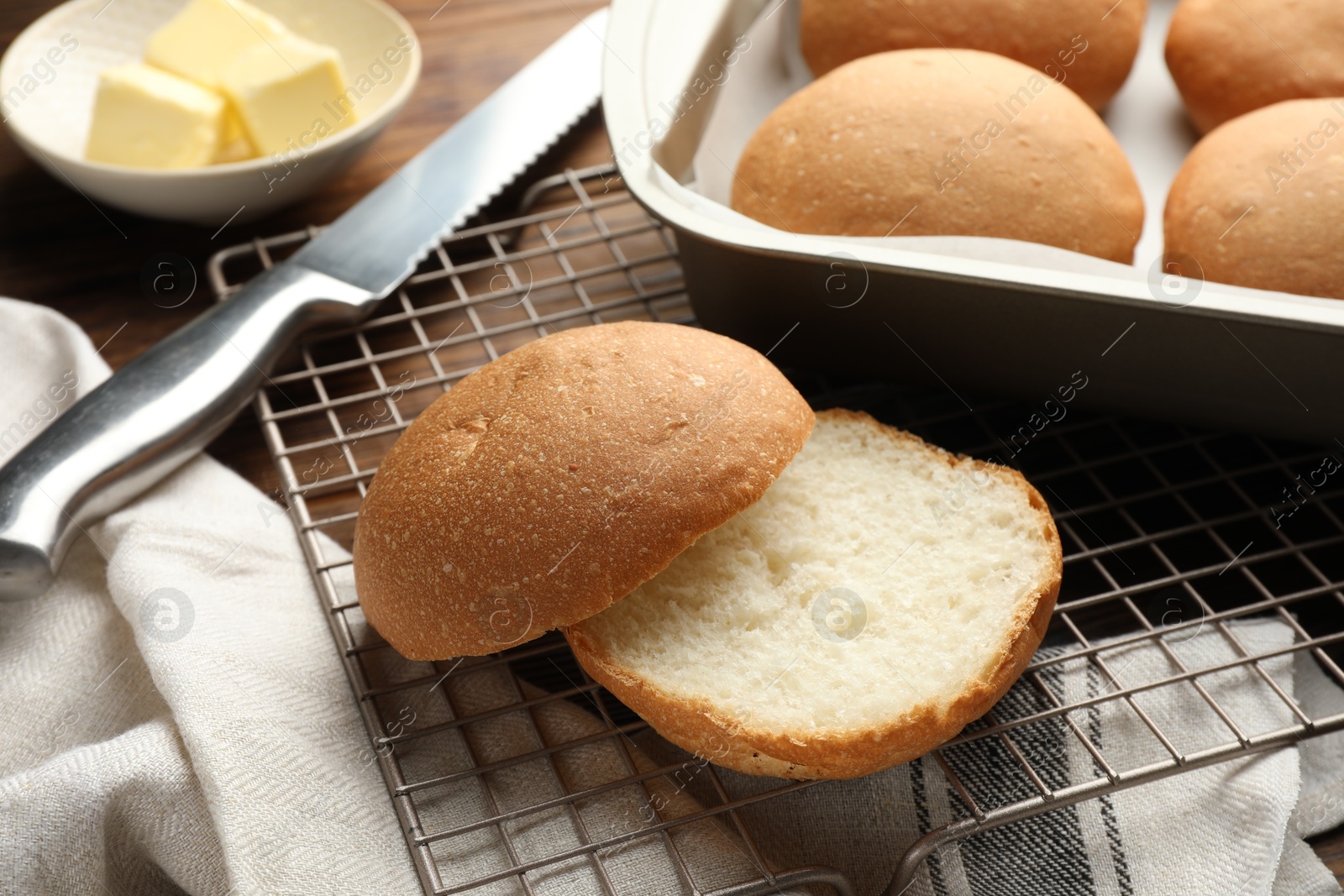 Photo of Fresh tasty buns, butter and knife on table, closeup