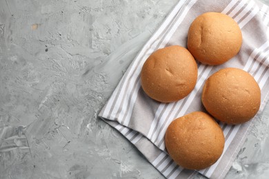 Photo of Fresh tasty buns on grey table, top view. Space for text