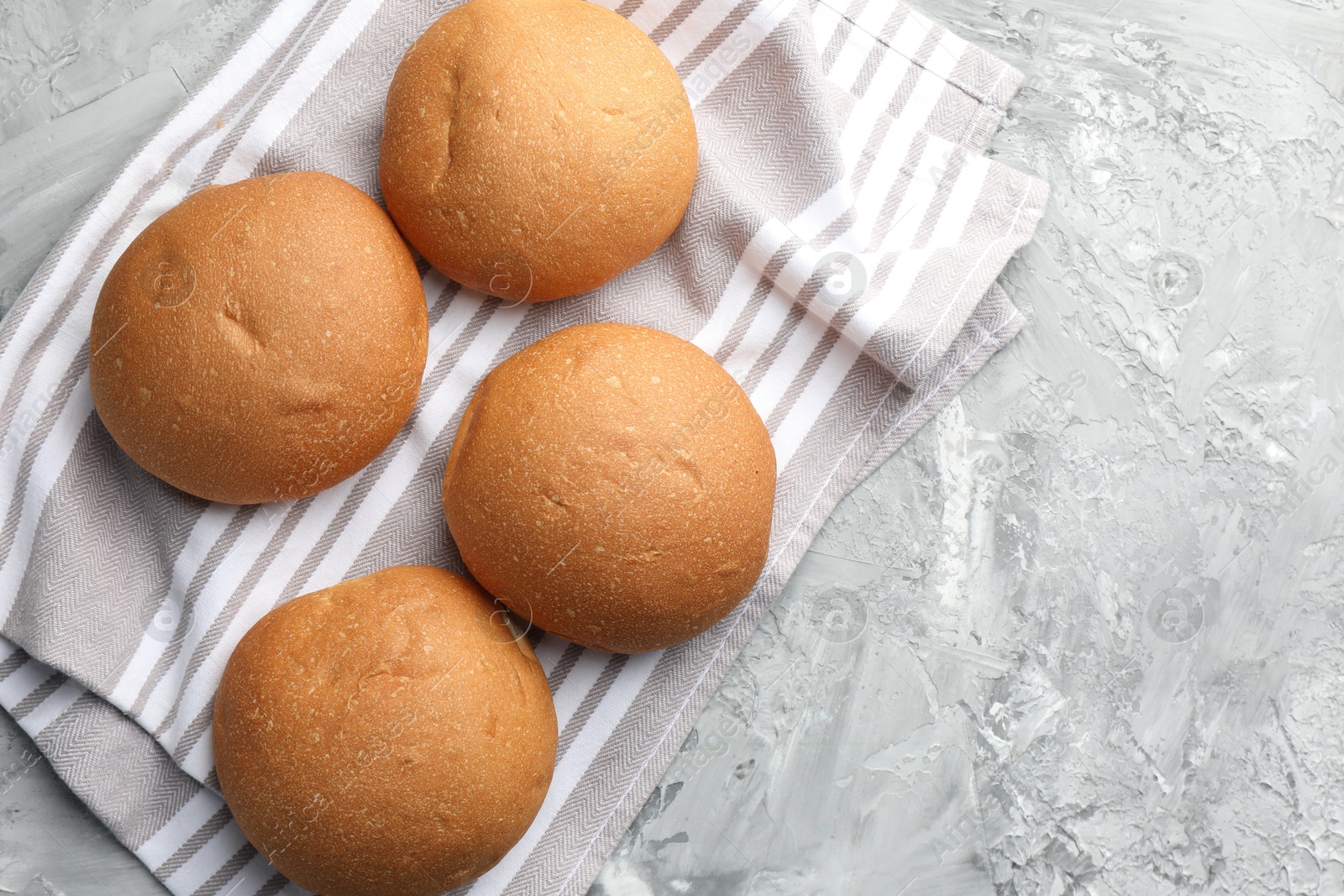 Photo of Fresh tasty buns on grey table, top view. Space for text