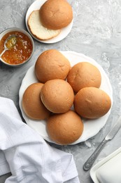 Fresh tasty buns and jam on grey table, top view