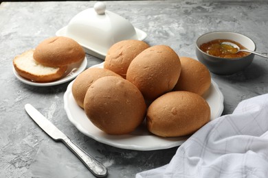 Fresh tasty buns and jam on grey table