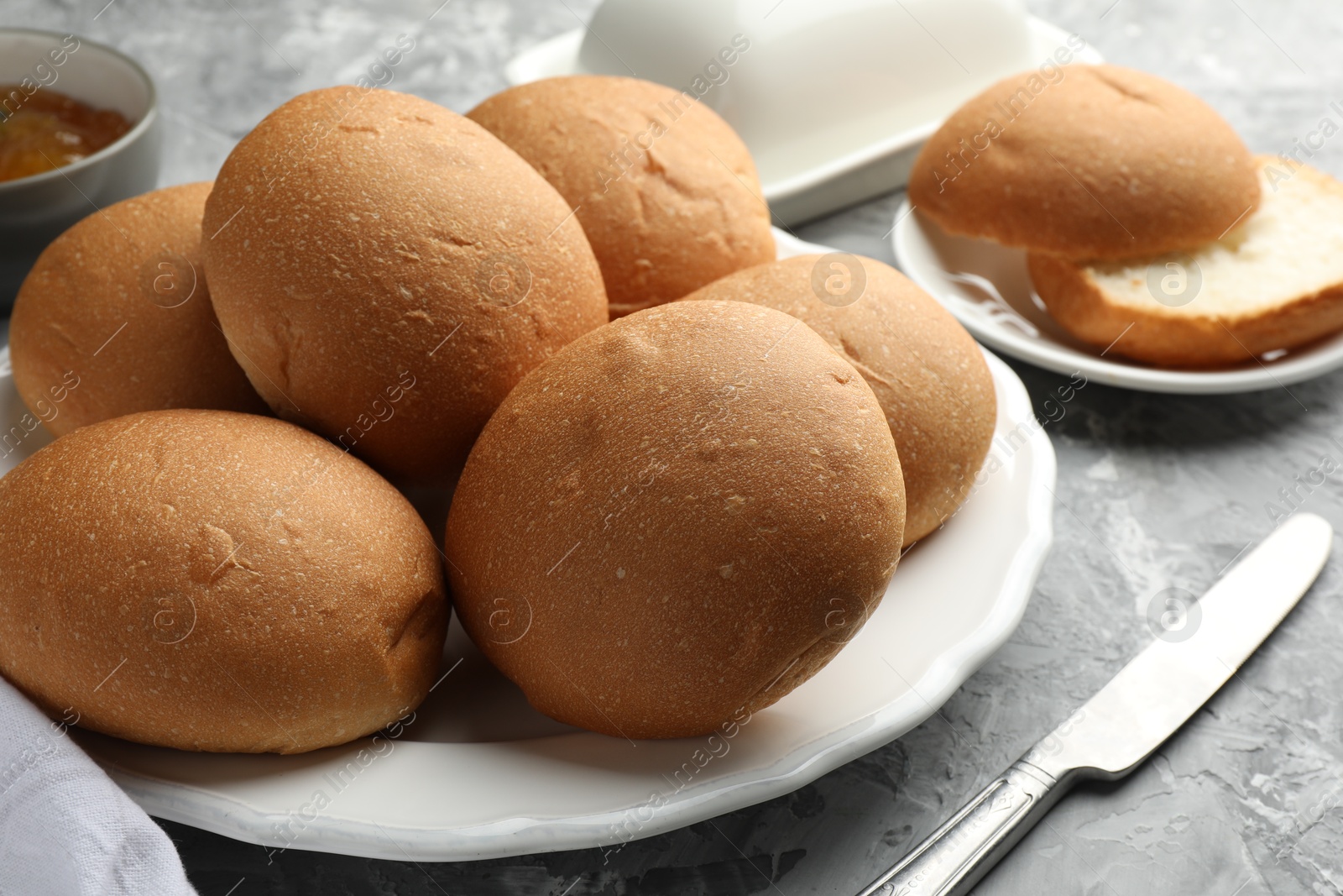 Photo of Fresh tasty buns on grey table, closeup