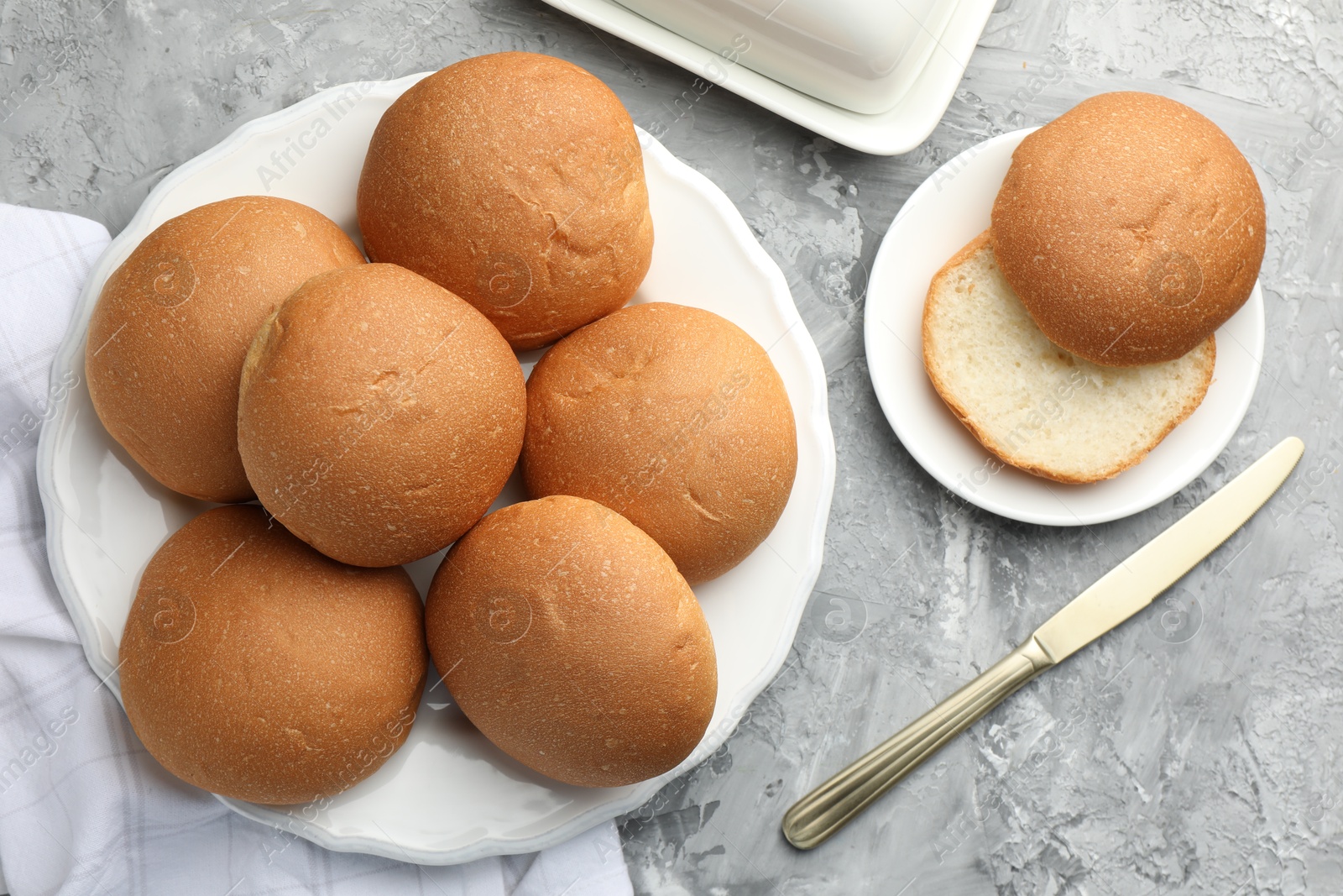 Photo of Fresh tasty buns and knife on grey table, top view